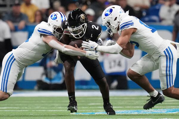 Colorado quarterback Shedeur Sanders (2) is hit by BYU linebackers Harrison Taggart, left, and Isaiah Glasker, right, during the first half of the Alamo Bowl NCAA college football game, Saturday, Dec. 28, 2024, in San Antonio. (AP Photo/Eric Gay)