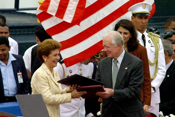 FILE - Former President Jimmy Carter, right, exchanges documents with Panamanian President Mireya Moscoso, Dec. 14, 1999, during a ceremony outside Panama City to transfer control of the Panama Canal to Panama after 85 years of American control on Dec. 31. (AP Photo/Tomas Van Houtryve, File)