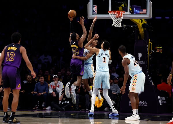 Los Angeles Lakers forward Rui Hachimura (28) goes up for a layup against San Antonio Spurs guard Devin Vassell, center, and center Victor Wembanyama (1) during the first half of an NBA basketball game Monday, Jan. 13, 2025, in Los Angeles. (AP Photo/Kevork Djansezian)