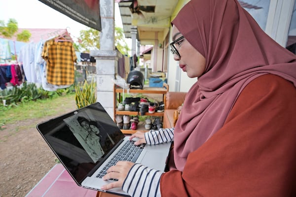 Qurrata Ayuni, a 28-year-old tsunami survivor, looks at the photo of her parents who were killed during the disaster, in Banda Aceh, Indonesia, Friday, Dec. 13, 2024. (AP Photo/Achmad Ibrahim)