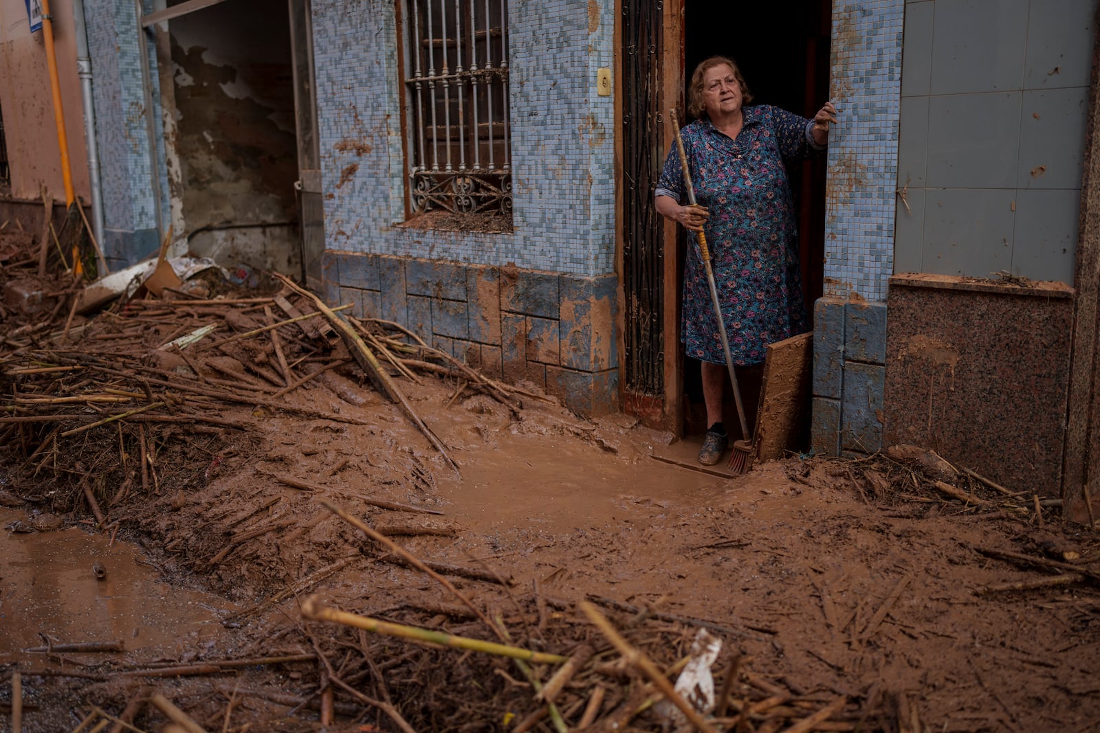 A woman stands in her house covered of mud in an area affected by floods in Valencia, Spain, Saturday, Nov. 2, 2024. (AP Photo/Manu Fernandez)