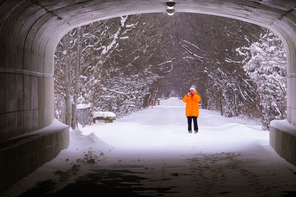 A walker pauses to take a photo as she walks along the snow-covered Monon Trail in Carmel, Ind., Monday, Jan. 6, 2025. (AP Photo/Michael Conroy)