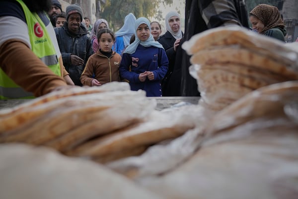 Turkish charity organisation Fetih distributes bread at the Yarmouk Palestinian refugee camp inn the outskirts of Damascus Thursday Dec. 12, 2024. (AP Photo/Hussein Malla)