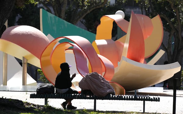 Manuel Rodriguez, 62, who is homeless, drinks a hot cup of coffee while he sits on a park bench with his belongings as temperatures are forecast to be in the forties this evening Wednesday, Jan. 8, 2025, in Miami. (AP Photo/Lynne Sladky)