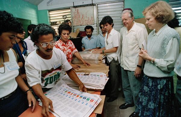 FILE - Former President Jimmy Carter and his wife Rosalynn, right, watch election workers prepare ballots at a polling station in Managua, Nicaragua, Feb. 25, 1990. The Carters are in Nicaragua to monitor the elections. (AP Photo/J. Scott Applewhite, File)