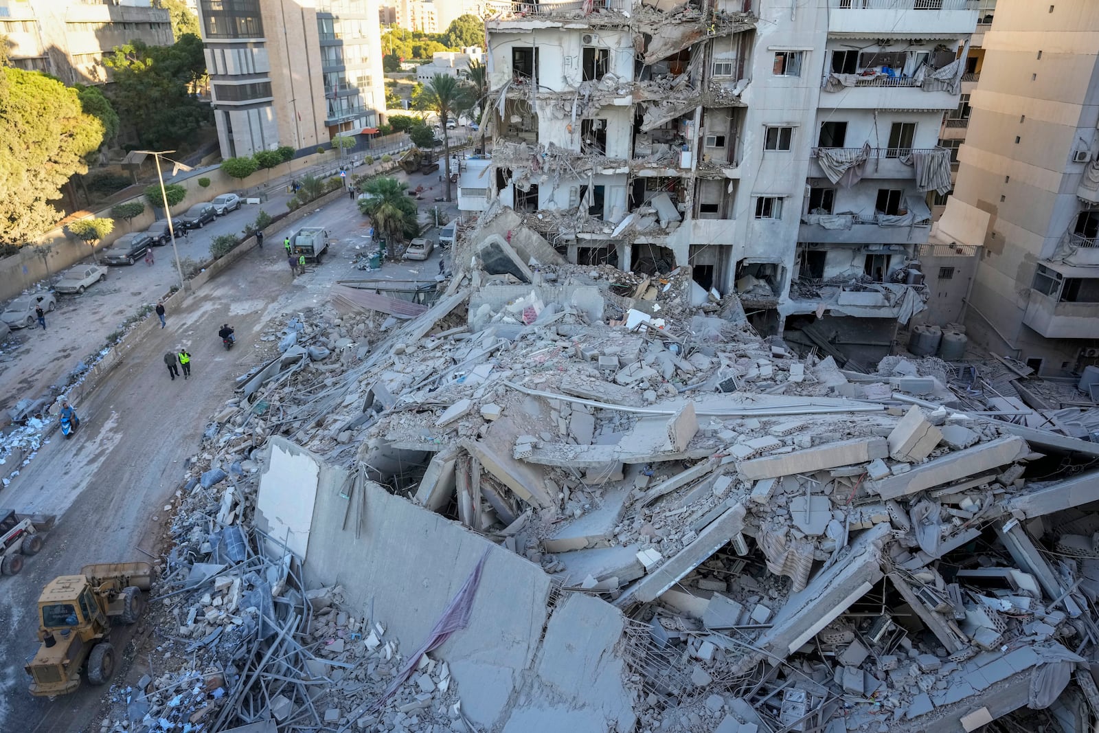 Rescue workers use a bulldozer to remove rubble of destroyed buildings at the site of an Israeli airstrike on Sunday night that hit several branches of the Hezbollah-run Qard al-Hassan Association in Beirut's southern suburb, Lebanon, Monday, Oct. 21, 2024. (AP Photo/Hassan Ammar)