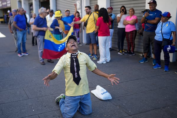 A man wearing the phrase in Spanish "Fight for freedom" kneels during a demonstration by opponents of Venezuelan President Nicolas Maduro the day before his inauguration for a third term in Caracas, Venezuela, Thursday, Jan. 9, 2025. (AP Photo/Matias Delacroix)