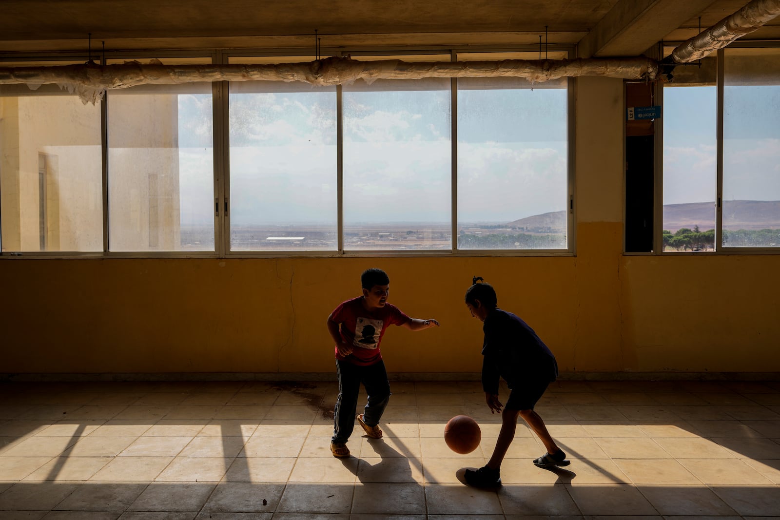 Displaced children, who fled Baalbek city and the nearby towns of Douris and Ain Bourday with their families amid the ongoing Hezbollah-Israel war, play at a school being used as a shelter, in Deir Al-Ahmar, east Lebanon, Thursday, Oct. 31, 2024. (AP Photo/Hassan Ammar)