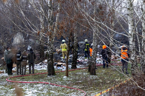 Lithuanian Emergency Ministry employees work near the place where a DHL cargo plane crashed into a house near the Lithuanian capital Vilnius, Lithuania, Lithuania, Monday, Nov. 25, 2024. (AP Photo/Mindaugas Kulbis)