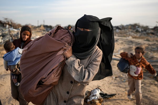 Azhar Abu Sheiban, center, and her family members return to their home in Rafah, days after the ceasefire deal between Israel and Hamas, southern Gaza Strip, Tuesday, Jan. 21, 2025. (AP Photo/Abdel Kareem Hana)