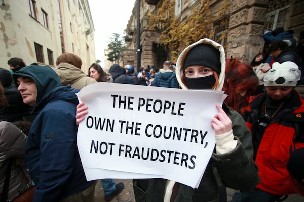 A protester holds a poster as they gather in a street during a rally to demand new parliamentary elections in the country, near the Parliament's building in Tbilisi, Georgia, on Monday, Nov. 25, 2024. (AP Photo/Zurab Tsertsvadze)