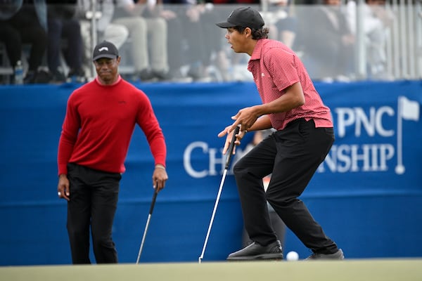 Tiger Woods, left, and Charlie Woods react after missing a putt during a playoff hole on the 18th green to win the PNC Championship golf tournament, Sunday, Dec. 22, 2024, in Orlando, Fla. (AP Photo/Phelan M. Ebenhack)