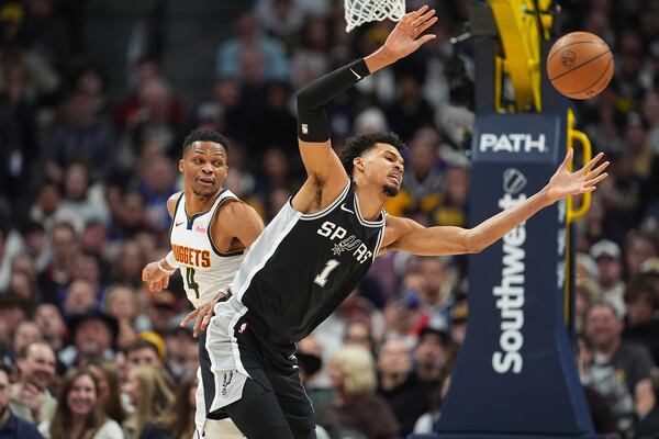 San Antonio Spurs center Victor Wembanyama, front, fights for control of a loose ball with Denver Nuggets guard Russell Westbrook in the first half of an NBA basketball game Friday, Jan. 3, 2025, in Denver. (AP Photo/David Zalubowski)