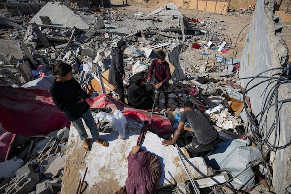 Members of the Abu Al Zamar family salvage items from under the rubble of their destroyed family home, in Rafah, southern Gaza Strip, Tuesday, Jan. 21, 2025, days after the ceasefire deal between Israel and Hamas came into effect. (AP Photo/Abdel Kareem Hana)