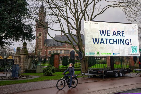 Activists put up a billboard outside the International Court of Justice, in The Hague, Netherlands, as it opens hearings into what countries worldwide are legally required to do to combat climate change and help vulnerable nations fight its devastating impact, Monday, Dec. 2, 2024. (AP Photo/Peter Dejong)