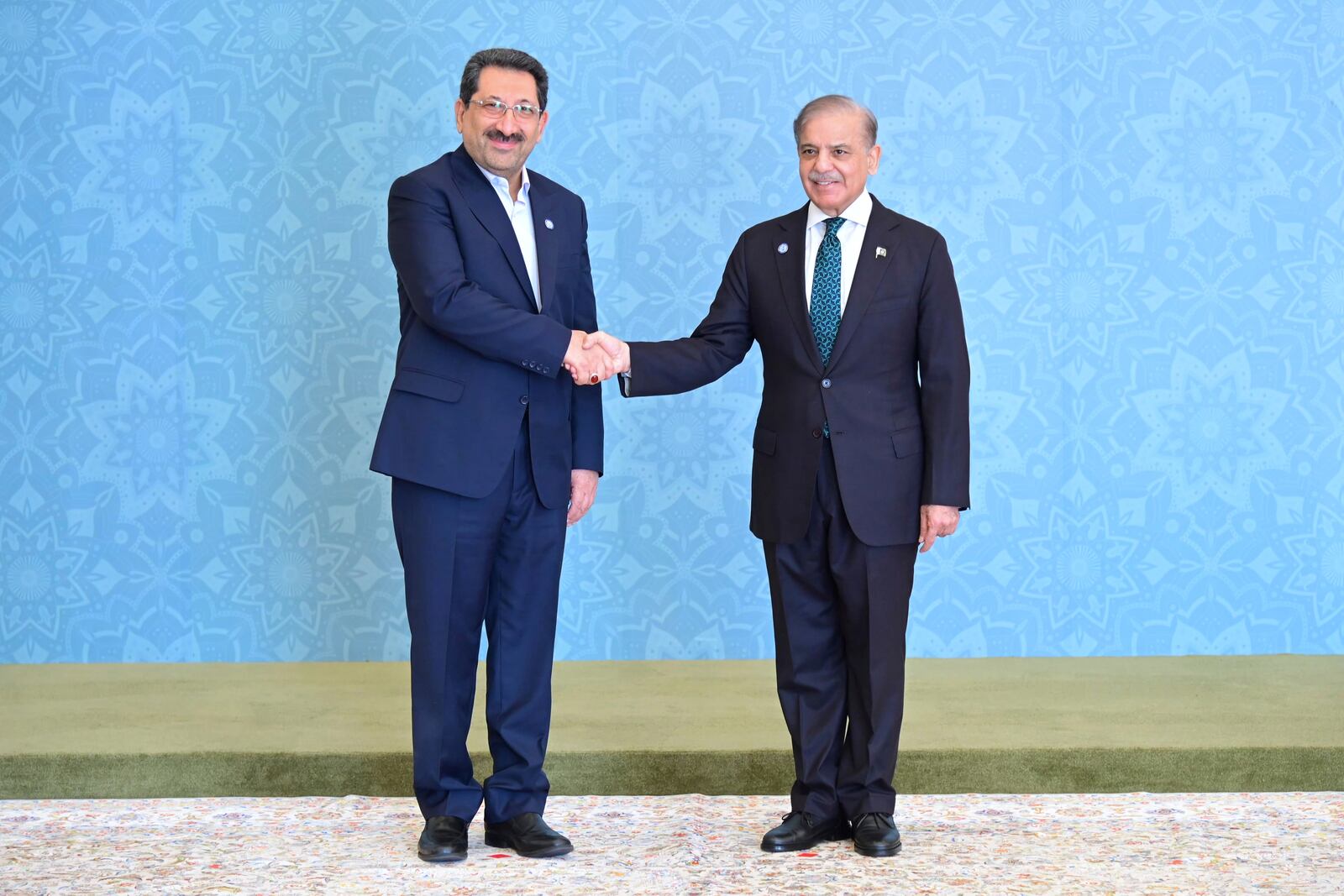 In this photo released by the Press Information Department, Iranian Minister for Industry, Trade and Mining Seyed Mohammad Atabak, left, shakes hand with Pakistani Prime Minister Shehbaz Sharif as he arrives to attend Shanghai Cooperation Organization (SCO) meeting, in Islamabad, Pakistan, Wednesday, Oct. 16, 2024. (Press Information Department via AP)