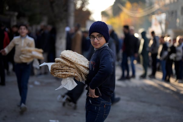 A Syrian boy look on as he carries bread in the city of Aleppo, Syria, Saturday, Dec. 14, 2024. (AP Photo/Khalil Hamra)