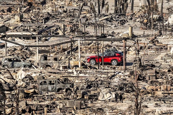 A car drives past homes and vehicles destroyed by the Palisades Fire at the Pacific Palisades Bowl Mobile Estates on Jan. 12, 2025, in Los Angeles. (AP Photo/Noah Berger)