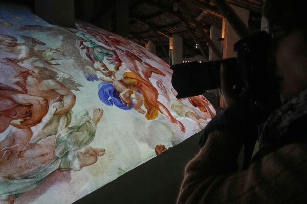 A photographer takes pictures during the preview to the press of the exhibition 'Petros eni', which is part of the project "St. Peter's Basilica: AI-Enhanced Experience" at the Vatican, Saturday, Nov. 9, 2024. (AP Photo/Gregorio Borgia)