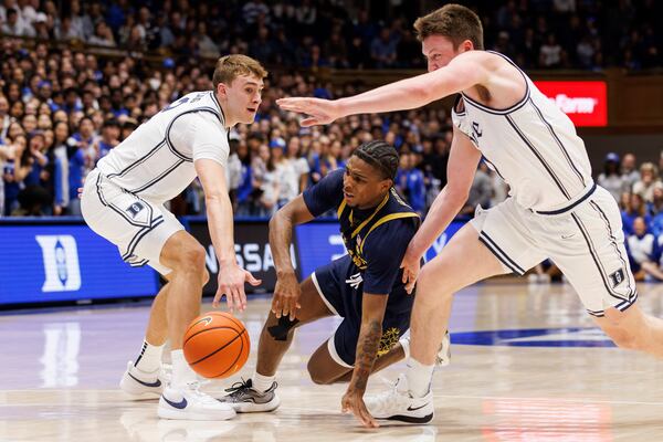 Notre Dame's Markus Burton, center, falls while handling the ball between Duke's Cooper Flagg, left, and Duke's Kon Knueppel during the first half of an NCAA college basketball game in Durham, N.C., Saturday, Jan. 11, 2025. (AP Photo/Ben McKeown)