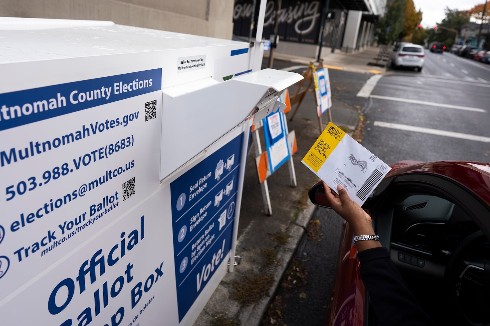 A voter drops off a ballot for the 2024 election in a newly installed drop box at the Multnomah County Elections Division office on Monday, Oct. 28, 2024, in Portland, Ore., after the pervious drop box was damaged. (AP Photo/Jenny Kane)