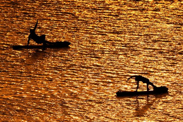 FILE - People do yoga poses on paddleboards at sunset at Olathe Lake on July 15, 2024, in Olathe, Kan. (AP Photo/Charlie Riedel, File)