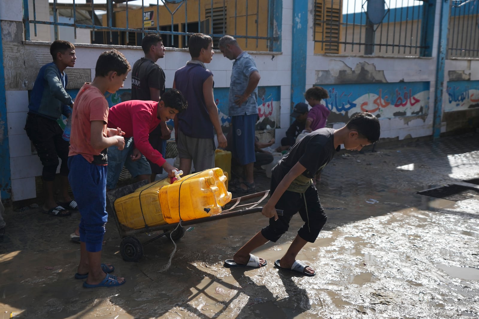 Palestinians collect clean drinking water at a desalination plant that now operates round the clock in Deir al-Balah, Gaza, a resource they barely had any access to during the war, Thursday, Nov. 14, 2024. (AP Photo/Abdel Kareem Hana)