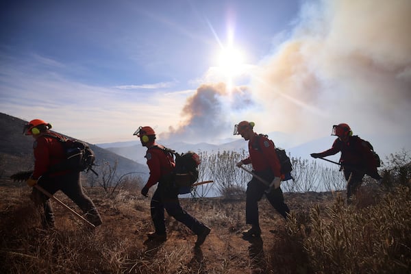 Firefighters walk along a mountainside to battle the spread of the Hughes Fire in Castaic, Calf., Wednesday, Jan. 22, 2025. (AP Photo/Ethan Swope)