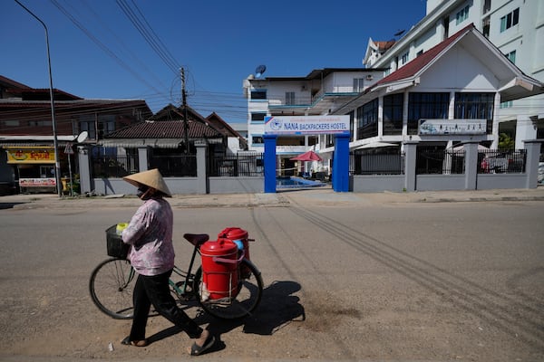 A woman with a bicycle walks pasts Nana Backpackers hostel in Vang Vieng, Laos, Friday, Nov. 22, 2024. (AP Photo/Anupam Nath)