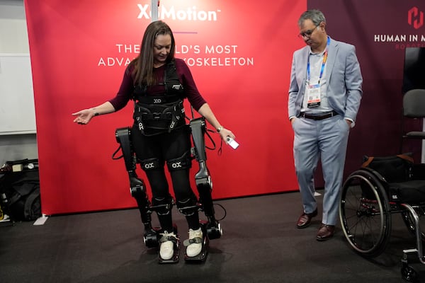 Chloe Angus, director of Lived Experience at Human in Motion Robotics and paraplegic, stands and moves with help from the XoMotion exoskeleton at the Human In Motion Robotics booth during the CES tech show Wednesday, Jan. 8, 2025, in Las Vegas. The wearable robotic exoskeleton is designed to assist patients with mobility impairments due to spinal cord injuries, stroke and other neurological conditions in standing up and walking. (AP Photo/John Locher)