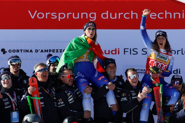 Italy's Sofia Goggia, center, winner of an alpine ski, women's World Cup downhill, and Italy's Federica Brignone, third placed, celebrate with the team at the finish area of an alpine ski, women's World Cup downhill, in Cortina d'Ampezzo, Italy, Saturday, Jan. 18, 2025 (AP Photo/Alessandro Trovati)