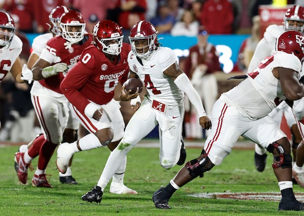 Alabama quarterback Jalen Milroe (4) runs the ball beside Oklahoma defensive lineman David Stone (0) during the second quarter of a NCAA college football game Saturday, Nov. 23, 2024, in Norman, Okla. (AP Photo/Alonzo Adams)