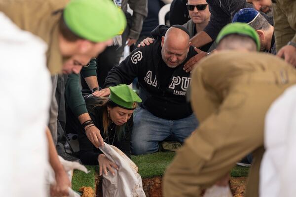 Gali and Nir, the parents of Israeli soldier Sergeant Yahav Maayan who was killed in combat in the Gaza Strip, react next to his grave during his funeral at a military cemetery in Modiin, Israel, Sunday, Jan. 12, 2025. (AP Photo/Ohad Zwigenberg)