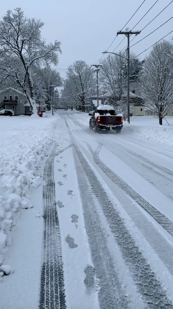 A vehicle drives on a snowy street in Lowville, N.Y., on Saturday, Nov. 30, 2024. (AP Photo/Cara Anna)