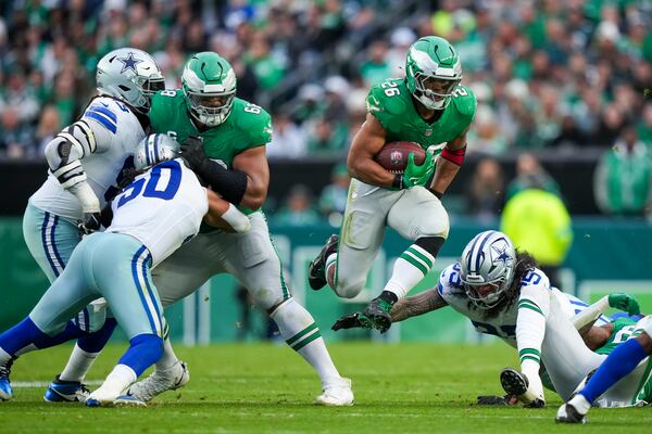 Philadelphia Eagles running back Saquon Barkley, center, leaps as Dallas Cowboys linebacker Marist Liufau tries to trip him up during the second half of an NFL football game, Sunday, Dec. 29, 2024, in Philadelphia. (AP Photo/Matt Slocum)