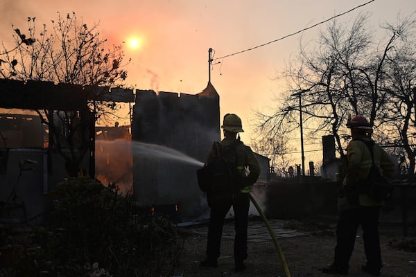 Firefighters water down a home after the Eaton Fire burns in Altadena, Calif., Thursday, Jan. 9, 2025. (AP Photo/Nic Coury)