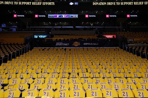 Jerseys with the number of former Los Angeles Lakers player Michel Cooper are left for fans on seats before an NBA basketball game between the Lakers and the San Antonio Spurs, Monday, Jan. 13, 2025, in Los Angeles. Cooper's No. 21 jersey will be raised into the rafters during halftime. (AP Photo/Kevork Djansezian)