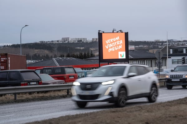 Cars drive past a bilboard of the Left Green Party (Vinstri græn) reading "Let's stay on the left side, in Reykjavik, Iceland, Friday, Nov. 29, 2024. (AP Photo Marco Di Marco)