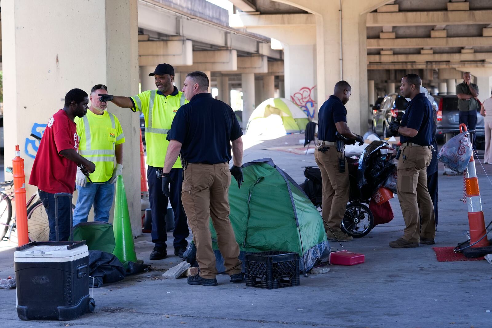 Louisiana State police give instructions to people living in a homeless encampment to move to a different pre-designated location as they perform a sweep in advance of a Taylor Swift concert in New Orleans, Wednesday, Oct. 23, 2024. (AP Photo/Gerald Herbert)