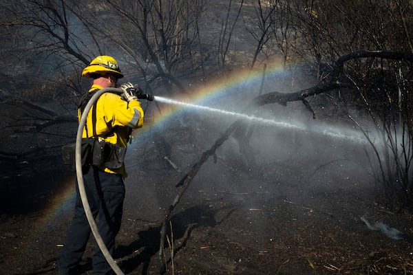 A firefighter hoses down hot spots from the Archer Fire in the Granada Hills section of Los Angeles, Friday, Jan. 10, 2025. (AP Photo/Ethan Swope)