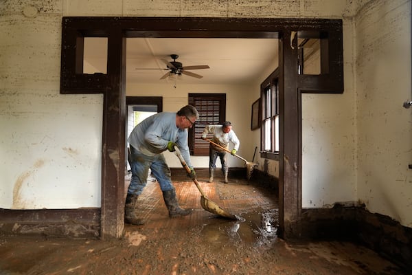 FILE - Ben Phillips, left, and his wife Becca Phillips scrape mud out of their living room in the aftermath of Hurricane Helene, in Marshall, N.C., Oct. 1, 2024. (AP Photo/Jeff Roberson, File)