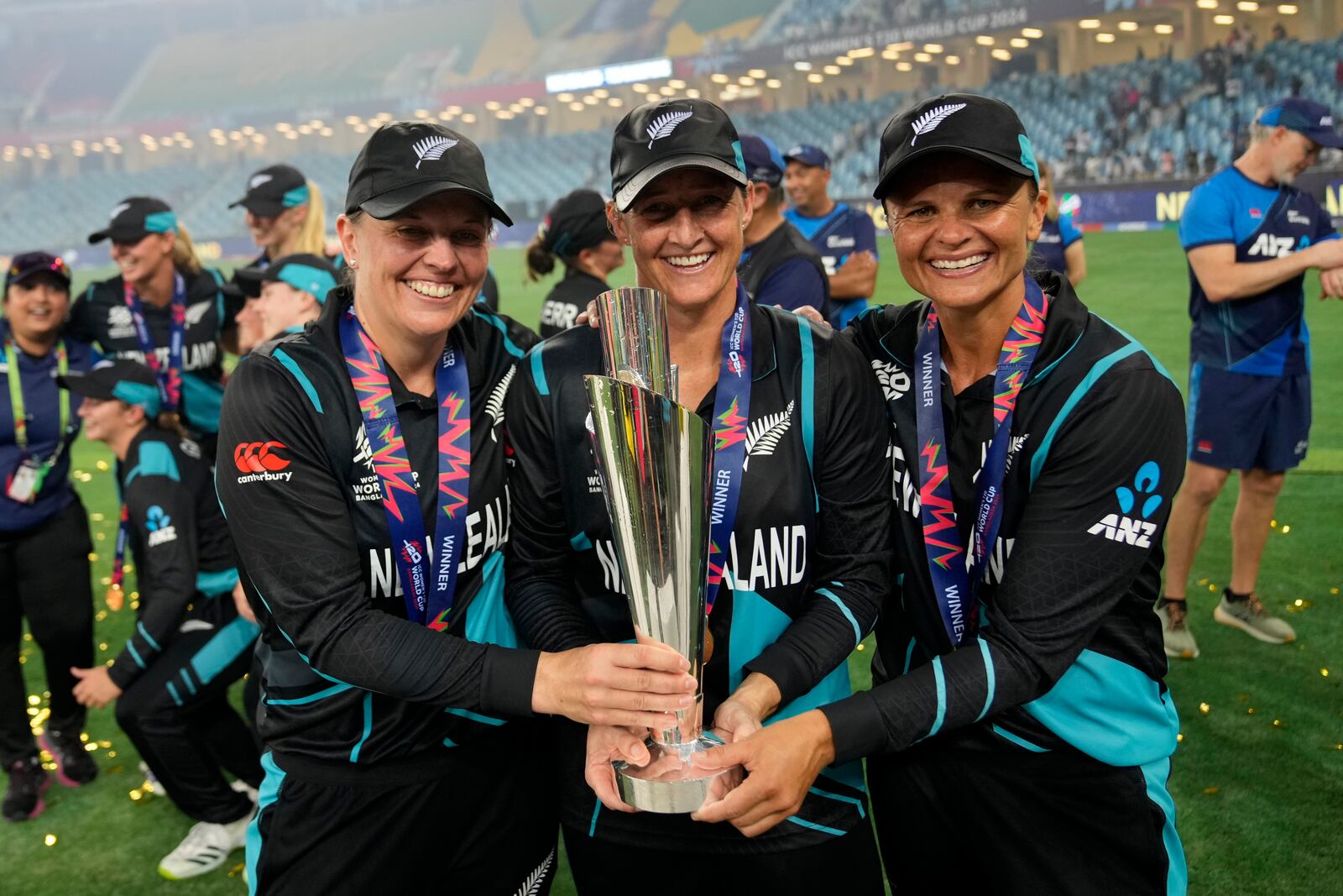 New Zealand's captain Sophie Devine, center, poses with teammates Lea Tahuhu, left, and Suzie Bates with the trophy after winning the ICC Women's T20 World Cup 2024 final match against South Africa at Dubai International Cricket Stadium, United Arab Emirates, Sunday, Oct. 20, 2024. (AP Photo/Altaf Qadri)