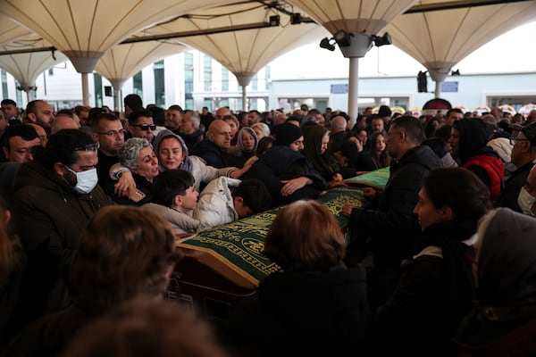 Relatives and friends mourn during the funeral of Yilmaz Saritas and his children Nehir and Doruk, who were among the 76 victims who died in a fire at the Kartalkaya ski resort in Bolu province, at Karsıyaka cemetery in Ankara, Wednesday, Jan. 22, 2025. (Ugur Yildirim/Dia Photo via AP)