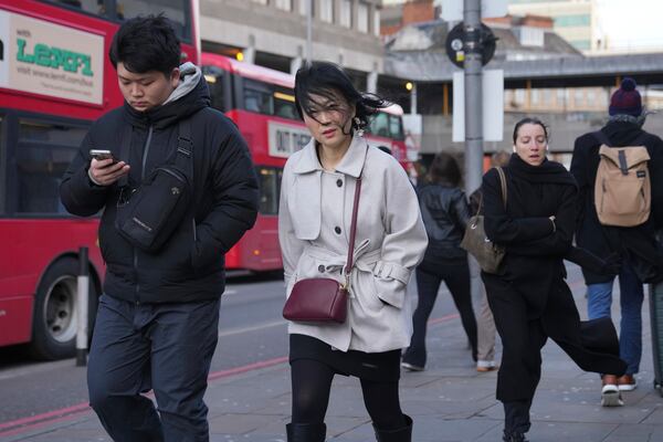 People brave the wind as storm Eowyn hits the country in London, Friday, Jan. 24, 2025. (AP Photo/Kin Cheung)