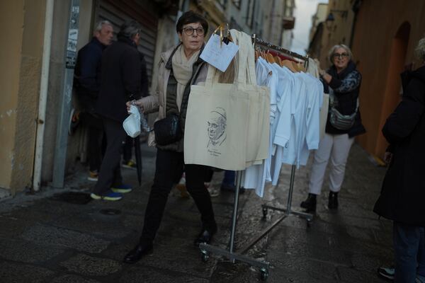 A woman carries bags bearing the Pope Franci' image prior to Pope's visit, in Ajaccio, in the southern French island of Corsica, Saturday, Dec. 14, 2024. (AP Photo/Thibault Camus)