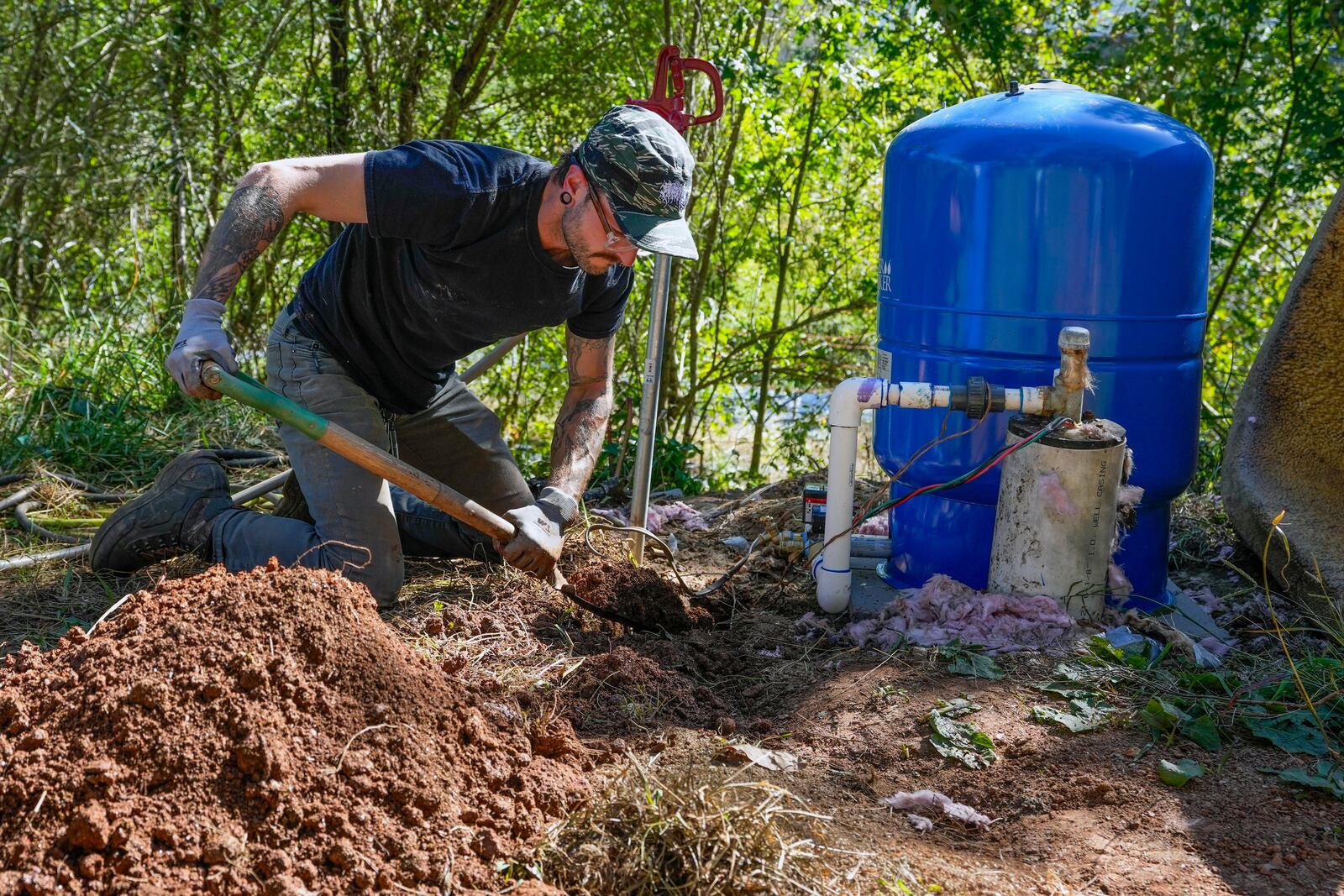 Volunteer, Anthony Rubino digs a ditch for pipes to connect water from a community well that will more easily provide the neighborhood with water, Monday, Oct. 14, 2024, in Asheville, N.C. (AP Photo/Kathy Kmonicek)