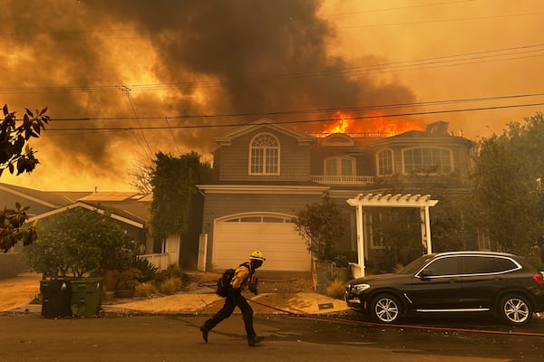 A residence burns as a firefighter battles the Palisades Fire in the Pacific Palisades neighborhood of Los Angeles Tuesday, Jan. 7, 2025. (AP Photo/Eugene Garcia)