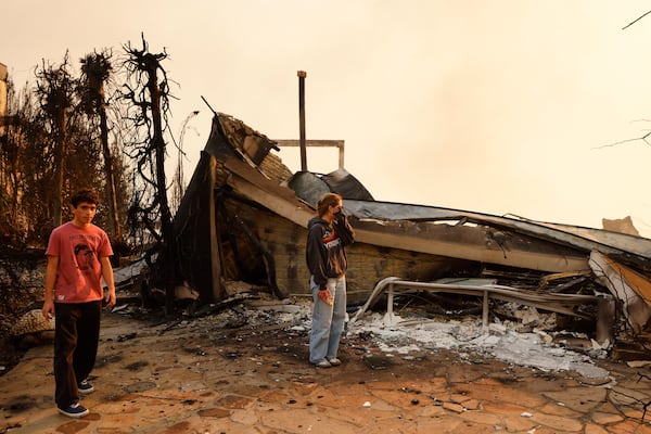 Fallon Prockiw-Kline, center, gets emotional in front of her home which was damaged by the Palisades Fire, Wednesday, Jan. 8, 2025, in Malibu, Calif. (AP Photo/Etienne Laurent)