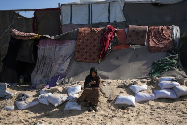 A woman sits outside a tent made locally from pieces of cloth and nylon, in a camp for internally displaced Palestinians at the beachfront in Deir al-Balah, central Gaza Strip, Friday, Dec. 27, 2024. (AP Photo/Abdel Kareem Hana)