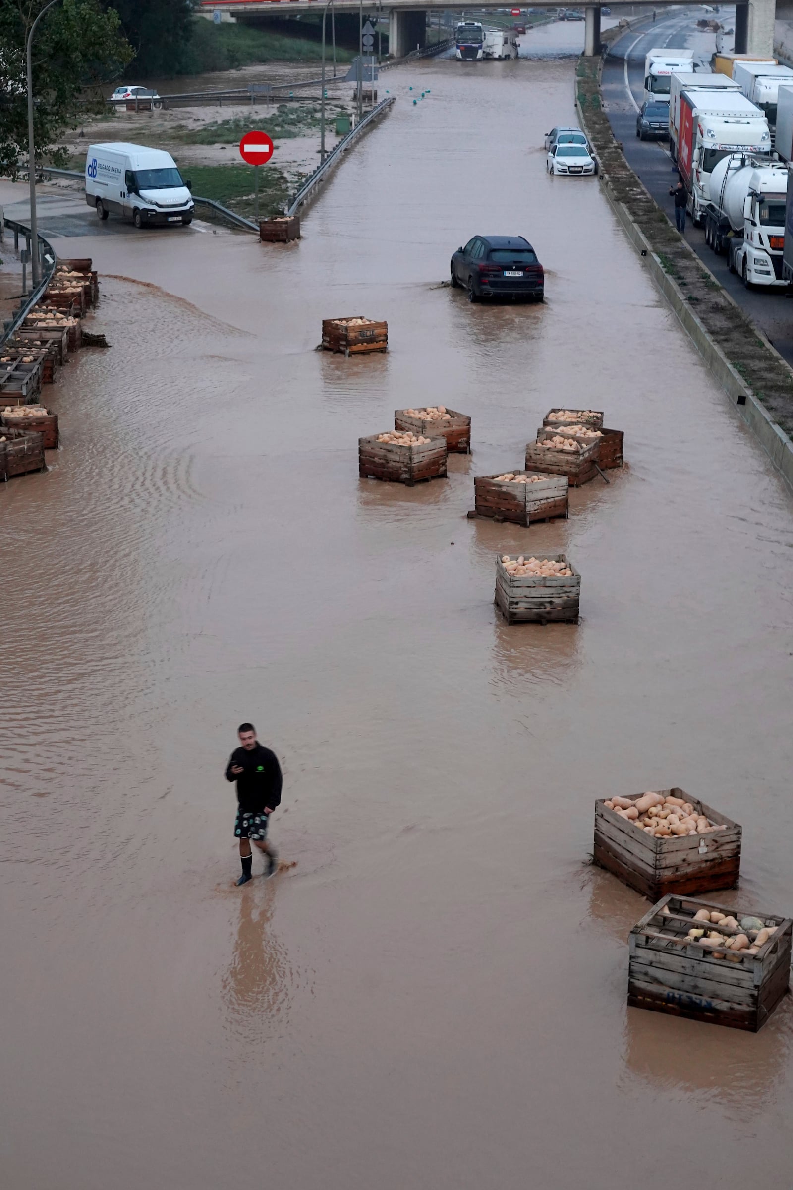 A man walks on a flooded motorway in Valencia, Wednesday, Oct. 30, 2024. (AP Photo/Alberto Saiz)